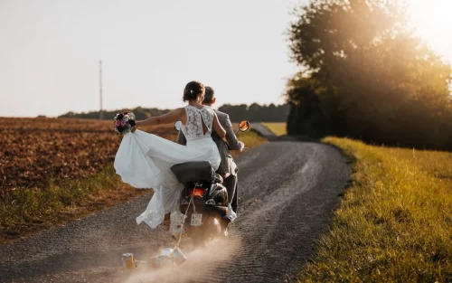 Brautpaar auf einem Roller fährt in Richtung Sonnenuntergang